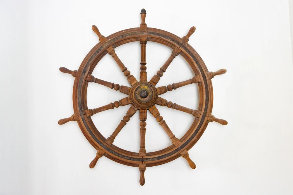 Wooden ship steering wheel mounted on wall.